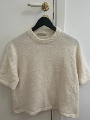 Kortärmad stickad tröja från Gina tricot  - Superfin kortärmad stickad tröja från Gina tricot i en vit färg. Tröjan har ribbade kanter vid hals, ärmslut och nederkant. Perfekt till lager-på-lager och funkar året runt. Enkel och stilren design som är lätt att matcha.