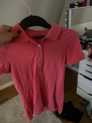 Rosa pikétröja från Gant XS - Säljer en klassisk rosa pikétröja från Gant i storlek XS. Toppen har korta ärmar, krage och knappar framtill. Tillverkad i mjuk bomull som känns skön mot huden. Perfekt för dig som gillar en sportig och stilren look.