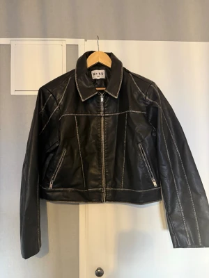 Svart skinnjacka från NA-KD -  NA-KD svart skinnjacka / bikerjacka (cropped) Snygg och trendig svart jacka från NA-KD.  Kort modell med markerade sömmar som ger en cool, edgy vibe. Perfekt till både vardag och utekväll – funkar lika bra till jeans som klänning.  Jackan har: Dragkedja framtill Två fickor med dragkedja Klassisk krage Mjuk och följsam kvalitet Använd en gång men i mycket fint skick, inga tecken på slitage. En riktig garderobsklassiker som aldrig går ur stil 🖤  📦 Skickas snabbt 🚭 Djur- och rökfritt hem 