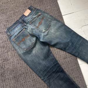 Mörkblåa Nudie Grim Tim Jeans - Riktigt feta Nudie jeans med sjuka fades. | W31 L32. | Riktigt bra skick, finns några små diskreta stilrena slitningar. | Väldigt tydliga honeycombs & whiskers. | Längd: 98cm, Midja: 38-43cm (Stretch). | Skriv vid minsta fundering, pris ej hugget i sten.