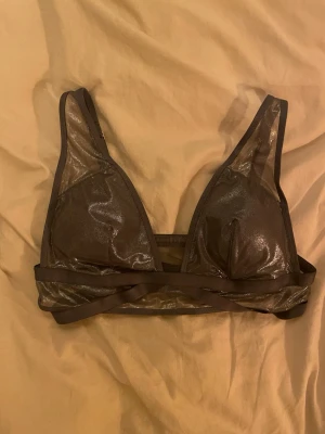 Glittrig BH från Victoria's Secret - Snygg  topp från Victoria's Secret med glittrigt tyg och triangelformade kupor. Justerbara axelband och bred resår under bysten för extra stöd.