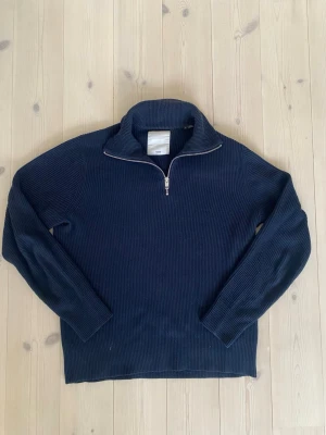 stickad half zip från Jack & Jones - Snygg marinblå stickad tröja från Jack & Jones med ribbad struktur och half zip-dragkedja i halsen. Tröjan har lång ärm och hög krage, perfekt för dig som gillar stilren och enkel design. Passar dig som vill ha en chill och klassisk look.