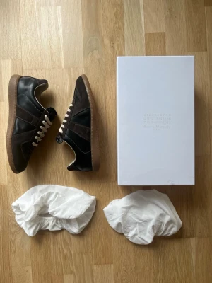 Maison Margiela Gats - Fina och unika Gats från Maison Margiela. Dem är använda men i väldigt fint skick, orginalbox medföljer och det enda som är slitet är insidan, därav priset. De är storlek 44 men skulle kunna passa ca 1 storlek åt båda hållen. Skriv vid funderingar🙌Pris kan diskuteras!