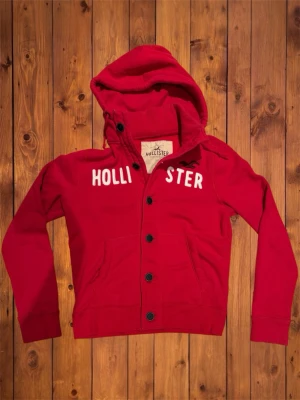 Vintage Hollister hoodie/cardigan (sällsynt) - Säljer denna vintage, sällsynta och asfeta hoodien/cardiganen från Hollister. Den är riktigt fet och har snygg design på framsidan. Priset är diskuterbart. Storlek är XL men den passar som M/L och se måtten nedan. B=67cm A=57cm