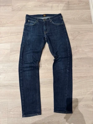 Lee Daren Zip Fly jeans - Mörkblå jeans från Lee, modell Daren Zip Fly. Klassisk femficksdesign med dragkedjegylf och raka ben. Snygga kontrastsömmar och Lee-logga på bakfickan. Tillverkade i slitstarkt jeanstyg som passar till det mesta.