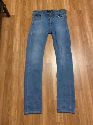 Replay blå jeans, storlek 28 - Säljer ett par klassiska blå jeans från Replay i storlek 28. Jeansen har raka ben, fem fickor och snygga kontrastsömmar. Materialet är slitstarkt jeans och passformen är normal. Perfekta till sneakers eller boots.