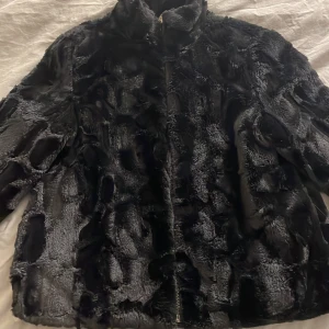 Svart pälsjacka från Pull&Bear - Säljer en svart pälsjacka från Pull&Bear i storlek S. Jackan har en fluffig och mjuk yta med snyggt mönstrad päls, hög krage och dragkedja framtill. Perfekt för dig som vill ha en cool och varm look under kyliga dagar.