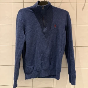 Blå half-zip från Polo Ralph Lauren i storlek S - Snygg blå polotröja från Polo Ralph Lauren i mjuk pima bomull. Tröjan har half zip-dragkedja, ribbad krage och långa ärmar. Klassisk röd broderad logga på bröstet. Nypris: 2400 kr, Mitt pris: 700 kr