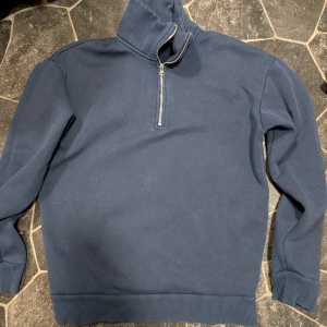 Marinblå half zip tröja från RYVLS stl 146-152 - Säljer en stilren marinblå tröja från RYVLS med half zip och hög krage. Tröjan har långa ärmar, ribbade muddar och är gjord i mjuk bomull. Perfekt för dig som gillar enkel och clean look med lite sportig vibe.