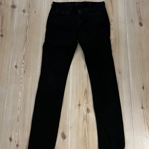 Levi's slight curve strl 29 - Svarta jeans från Levi's med klassisk midja och slim passform. Modellen är Slight Curve och har fem fickor, dragkedja och knappstängning. Jeansen är tillverkade i stretchigt denim för en bekväm känsla och sitter snyggt längs benen.