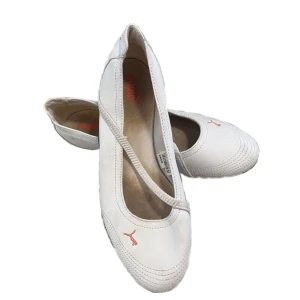 Vita ballerinaskor från Puma - Snygga vita ballerinaskor från Puma med diskret röd logga på ovansidan och hälen. Skorna har en elastisk rem över foten och en platt, svart sula med rött mönster undertill. 
