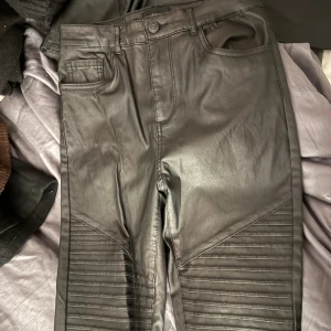 Svarta skinnbyxor från Vero Moda - Svarta byxor från Vero Moda med ribbade partier över knäna. 