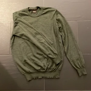 Grön stickad tröja från Oscar Jacobson - Riktigt fet Mörkgrön stickad tröja från Oscar Jacobson i storlek S. Tröjan har rund halsringning, långa ärmar och ribbade muddar vid ärmslut och nederkant. Perfekt för lager-på-lager under kyliga dagar. Skriv vid funderingar!