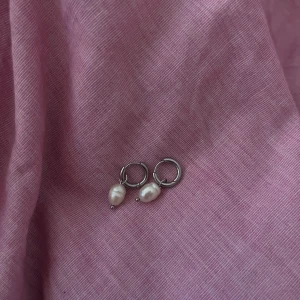 Rostfritt silverörhängen med vita pärlor💕 - Säljer ett par örhängen i silverfärgad rostfritt metall med hängande vita pärlor. Designen är enkel med små ringar och droppformade pärlor som ger en fräsch och modern vibe. Perfekt för dig som gillar minimalistiska smycken med en touch av elegans.💕💕