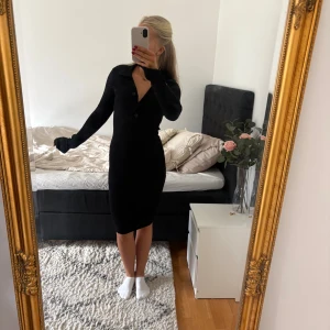 Svart ribbstickad klänning  - Från Gina tricot I strl S. Sitter figurnära men tyget är mycket elastiskt. Knappar och v-ringning vid halsen och slits i armarna. Använd några gånger men fortfarande i fint skick.