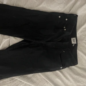 Jeans  lager 157 storl.M - Svarta byxor från 157 i modellen Snake Flare, storlek M och full längd. Byxorna har klassisk femficksdesign, silverfärgade knappar och dragkedja. Snyggt utsvängda ben för en trendig siluett, perfekta för dig som gillar att sticka ut.