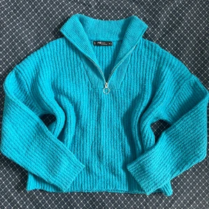 Turkos stickad tröja med half zip - Turkos stickad tröja från FB Sister med ribbad struktur och halv dragkedja framtill. Tröjan har hög krage och långa ärmar, perfekt för att hålla värmen. Snygg loose passform och cool färg som sticker ut. Storlek M.