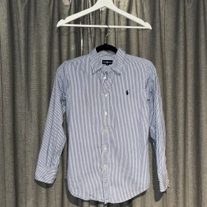 Blårandig skjorta från Ralph Lauren - Snygg Ralph lauren skjorta i perfekt skick. Storlek 14 passar dig som ungefär 160-165 lång. Hör av er vid frågor🙌