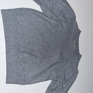 Grå stickad tröja🤍 - Mysig grå stickad tröja från ONLY i storlek XS. Tröjan har puffiga långärmar och ribbade muddar vid hals, ärmslut och nederkant. Perfekt för dig som gillar enkel och stilren look med en twist på ärmarna. Den är även lite nopprig men inga andra skador på tröjan💕