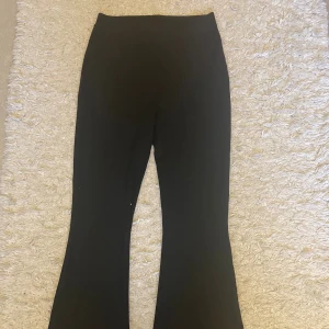 Svarta bootcut byxor från Lindex - Svarta bootcut byxor från Lindex i storlek 170. Byxorna har en hög midja och är tillverkade i ett mjukt och stretchigt material som sitter skönt. Snyggt utsvängda ben ger en trendig siluett. Perfekta för dig som gillar stilrena och bekväma plagg. Dessa är använda men i gott skick. 