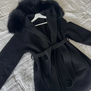 Svart kappa med päls - Svart pälskappa med band i midjan i storlek xs. Pälsen är avtagbar vid tvätt eller likande🫶🏽