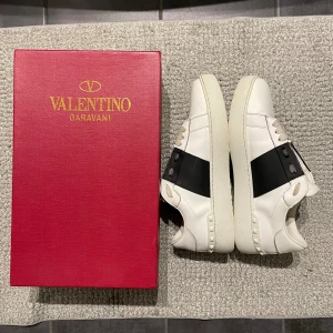 Valentino Open - Hej! Säljer mina valentino open i färgen Vit/Svart. Är i nytt skick. inga hål ingenting fel med dom. Haft dom i runt 6 månader. Säljer för jag inte tycker om dom längre. Allt ingår box, dustbag,påse, valentino kort och Valentino kuvär. Skriv om ni har några frågar🧩
