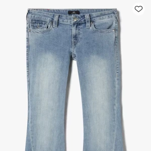 True Religion ljusblå bootcut jeans - Säljer ett par ljusblå jeans från True Religion med bootcut passform och klassiska broderade bakfickor. Jeansen har låg midja, fem fickor och snygga detaljer som silverfärgade knappar och logopatch bak. Perfekta för dig som gillar en avslappnad men trendig look. Dom är uppsydda där nere men det syns inte, då det är riktigt proffesionellt gjort. Så innerbenslängden är 77cm. 💕