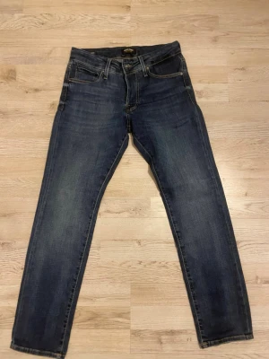Mörkblå jeans från Jack & Jones Slim Glenn - Säljer ett par mörkblå jeans från Jack & Jones med klassisk femficksdesign och snygga kontrastsömmar. Jeansen har slim passform och normal midja, tillverkade i slitstarkt bomullsmaterial. Perfekt för dig som gillar stilrena och tidlösa jeans. Jeansen är i perfekt och nytt skick och köptes igår.