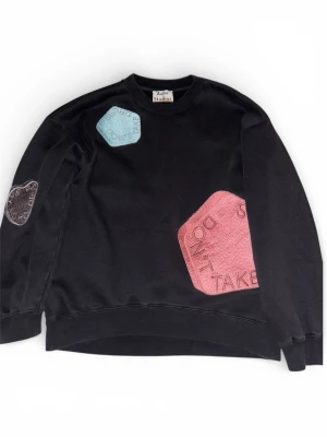 Svart sweatshirt Acne Studios M - Cool svart sweatshirt från Acne Studios med stora färgglada patches i blått, rosa och grått med text som 'Say No To Drugs'. Tröjan har rund hals och är tillverkad i mjuk bomull med polyesterkontrast. Perfekt för dig som gillar statement-plagg och unik design. Det står storlek XS men passar mer M