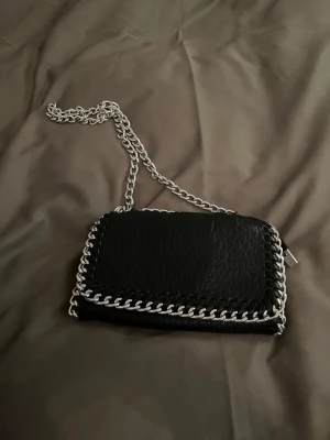 Svart väska  - Säljer en svart axelväska med silverfärgad kedja. Går att ha som axelväska samt crossbody. Skriv för fler bilder🩷