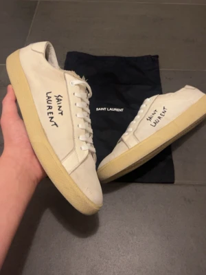 Saint Laurent skor - Säljer ett par vita Saint Laurent skor i Fint skick Skick: 8,3/10🧮  Inkluderat: endast skorna ingår♦️  Pris: 2799 kr ej hugget i sten🎗️  Storlek: 44 ♣️  Snabbaffär = priset sänks-SERIÖSA BUD🔓