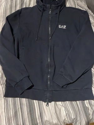 Ea7 Zip hoodie - Säljer nu min ea7 zip hoodie, i bra skick med någon mindre defekt. Köptes ny på zalando för 1500. Sitter som S/M. 