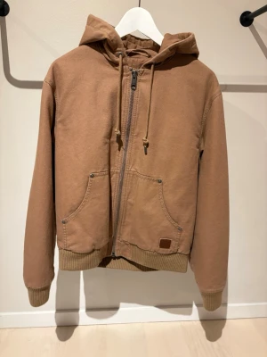 Varm gant jacka  - Säljer en brun jacka från GANT med dragkedja och snörning i huvan. Jackan har två stora fickor framtill och ribbade muddar vid ärmslut och nederkant. Perfekt för chill dagar och enkel att matcha med jeans eller joggers. Väldigt varm också