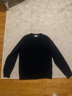 Svart sweatshirt från Samsoe Samsoe - Säljer en stilren svart sweatshirt från Samsoe Samsoe. Tröjan har en klassisk rund hals och långärmade ärmar. Materialet är mjukt och har en lätt struktur som ger en cool känsla. Perfekt för dig som gillar enkel och snygg design.
