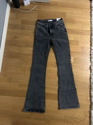 Bootcut jeans, Perfect Jeans  - Säljer ett par högmifjsde mörkgrå bootcut jeans från Perfect Jeans i storlek 36. De har klassisk femficksdesign, normal passform och är tillverkade i mjukt jeanstyg. Perfekt för dig som gillar en lite retro och avslappnad stil. Helt nyköpta och har aldrig användts.