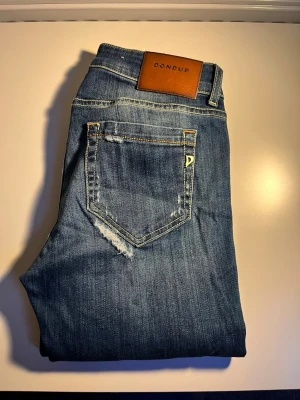 Dondup (Tara)  - Säljer ett par otroligt snygga Dondup jeans, paret har slitningar som du kan se på bild 2. Strl 30/27, kom gärna med bud! 😊 Ytterbens längd: 93cm  Innerbens längd: 67cm Midja: 35cm  Benöppningen: 14cm