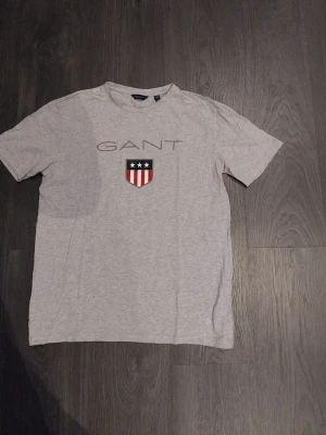 Gant T-Shirt - Säljer nu denna Gant  T-Shirt då den aldrig har använts. Den är i storlek 176 men sitter som S/M alltså lite större i storleken. Den passar när som helst på dagen/kvällen,på middagar eller bara i skolan. 