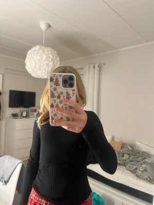 Svart ribbad topp från New Look - Svart långärmad topp från New Look i ribbad polyester med snörning i sidorna. Modellen är figurnära och har rund halsringning. Perfekt för dig som gillar stilrena och trendiga plagg med extra detalj i midjan.