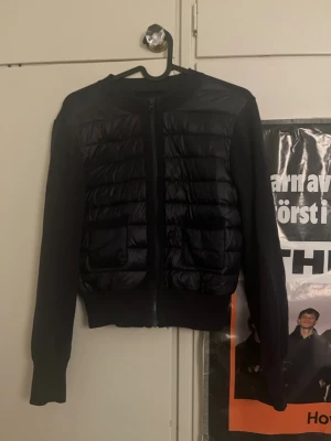 Svart pufferjacka från Gina Tricot - Säljer en svart pufferjacka från Gina Tricot i storlek 158/164. Jackan har quiltad framsida i glansigt material, två fickor framtill och dragkedja hela vägen. Ärmar och rygg är i mjuk stickad kvalitet för extra komfort.