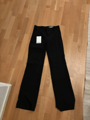 Svarta wide/bootcut kostymbyxor från Bershka - Säljer ett par svarta kostymbyxor från Bershka i storlek 34. Byxorna har en wide passform med raka ben och låg midja. Materialet är mjukt och har en snygg struktur.