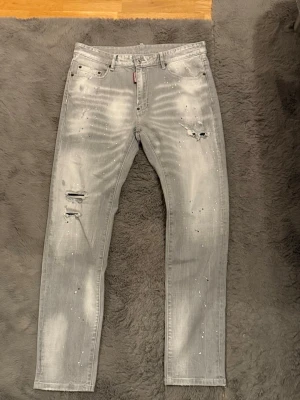 Grå slim jeans från Dsquared2 - Ett par riktigt schyssta dsquared2 jeans med unika detaljer i mycket fint skick! Färgstänk, slitningar you name it! Priset kan diskuteras och hör gärna av dig vid frågor! OBS Europeisk storlek (34) 