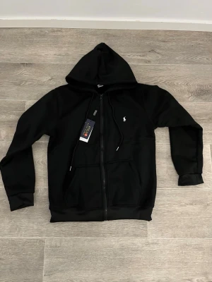 Svart tracksuit från Polo Ralph Lauren - Snygg tracksuit från Ralph lauren tracksuiten är Populär, Skön, Stilig och varm perfekt för kyliga dagar. Den perfekta klädsel om du vill bara chilla 