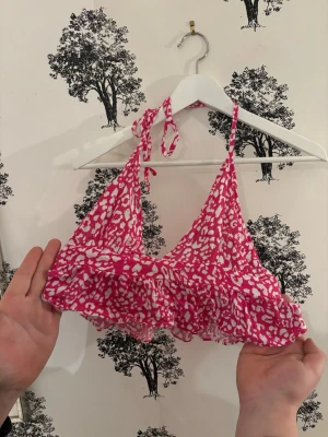 Rosa leopardmönstrad linnetopp  - Säljer en rosa och vit leopardmönstrad linnetopp från Shein i storlek XS. Toppen har knyt i nacken, volangkant nedtill och är ärmlös med omlott-design framtill. Perfekt för sommarens varma dagar och har en lätt och luftig känsla.