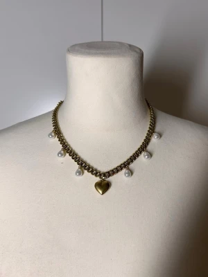Halsband med pärlor och hjärta guld  - Handgjort kedjehalsband med pärlor. Kedjan är 7mm bred och 45cm lång. Allt i rostfritt stål förutom pärlorna. Fast pris satt efter materialkostnader och tillverkning. Köp gärna via köp nu, snabb leverans.    