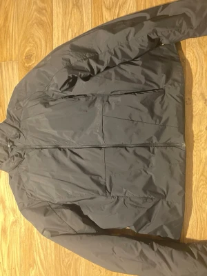 Svart vindjacka från Sail Racing - Svart vindjacka från Sail Racing i storlek XL (kids size)  Jackan har en stilren design med diskret logga på bröstet och dragkedja framtill. Materialet är lätt och syntetiskt, perfekt för blåsiga dagar. Långärmad och med normal passform. Köpt för 2800kr