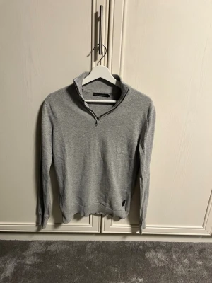 Grå half zip tröja från French Connection - Snygg grå långärmad tröja från French Connection med half zip och ståkrage. Tröjan är i mjuk bomull och har ribbade muddar vid ärmslut och nederkant. Perfekt för dig som gillar stilrena och enkla plagg med en modern touch. Skick 8/10 pris 249kr.
