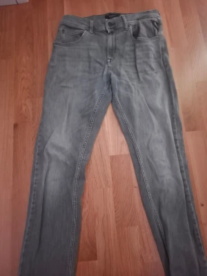 Replay Wallys grå jeans - Säljer ett par grå jeans från Replay, modell Wallys. De har klassisk femficksdesign, raka ben och snygga detaljer på bakfickan. Jeansen är tillverkade i mjukt denim-material och har en normal passform. Perfekta för dig som gillar stilrena och enkla jeans.