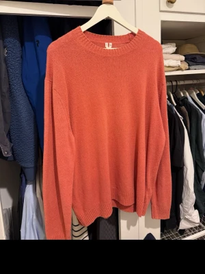 Koralröd stickad tröja XL - En stilren korallröd stickad tröja med rund halsringning och ribbade muddar vid ärmslut och nederkant. Perfekt för lager-på-lager och enkel att matcha med jeans eller kjol. Oversized fit för en avslappnad look.