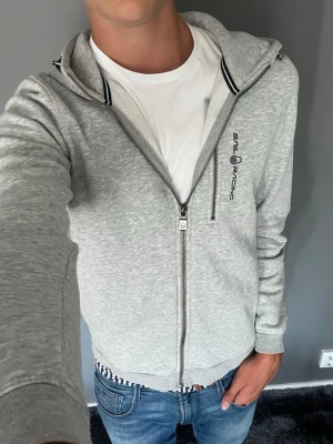 Sail racing zip hoodie - Säljer denna feta sail racing zip hoodie i en snygg grå färg! Hoodien är i storlek 176. 