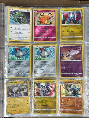 Samling Pokémonkort i plastperm  - Stor samling Pokémonkort med blandade motiv som Rayquaza, Dedenne, Salamence, Magemite, Articuno, Miradon, Dialga, Machamp, Tangela, Mareep, Ho-Oh, Reshiram, Cosmoem, Charmander, Pikachu och Dratini. Korten har färgstarka illustrationer och ligger i en plastperm. Perfekt för samlare eller Pokémonfans. Pokemonkorten har ett värde på över 500 kr! Innehåller både äldre och nya kort! 